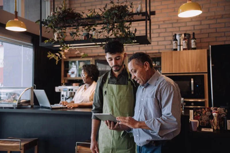 Manager and employee reviewing workforce scheduling on a tablet in a modern workplace — WorkEasy Software for every industry